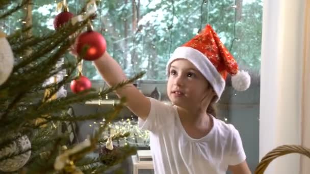 Liten söt flicka med sin mamma dekorera julgran — Stockvideo