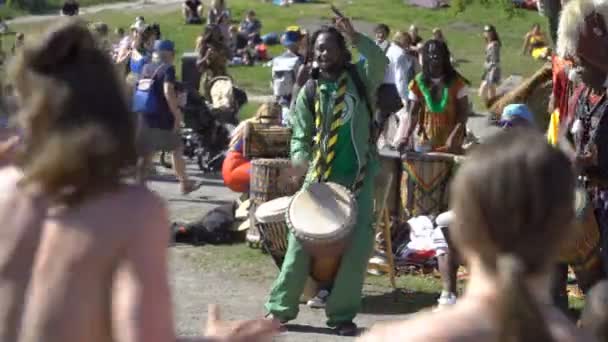 Jóvenes nativos de África y los lugareños bailan y tocan tambores tradicionales en un parque de la ciudad en Helsinki . — Vídeos de Stock