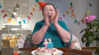 Ailesiyle video sohbet etmek yolu ile birlikte Doğum günü kutlamaları sırasında kamera için pasta tutarak mutlu kadın kıdemli