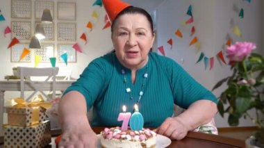 Ailesiyle video sohbet etmek yolu ile birlikte Doğum günü kutlamaları sırasında kamera için pasta tutarak mutlu kadın kıdemli