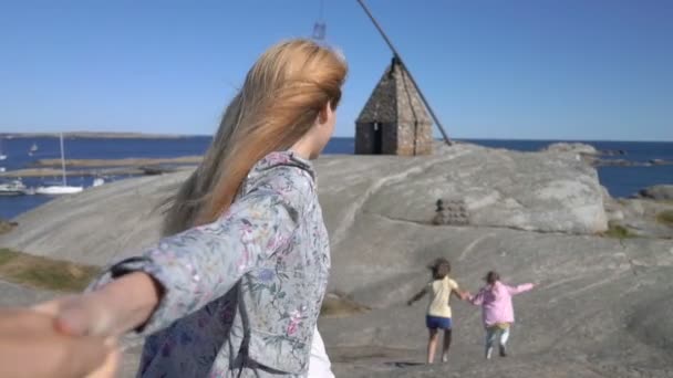 Mujer joven con niños Guiando a su marido caminando hacia la playa rocosa del norte — Vídeo de stock