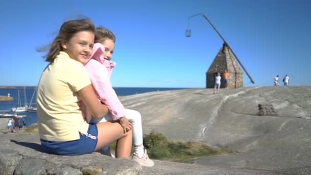 二人の少女がビーチで遊ぶ海岸の岩の間. — ストック動画