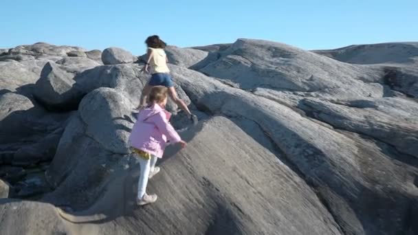 Dos niñas juegan entre las rocas costeras de la playa . — Vídeo de stock