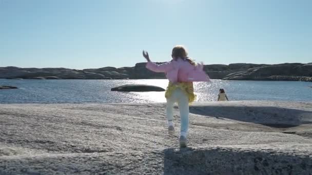 Två små flickor spela bland kustnära stenarna på stranden. — Stockvideo