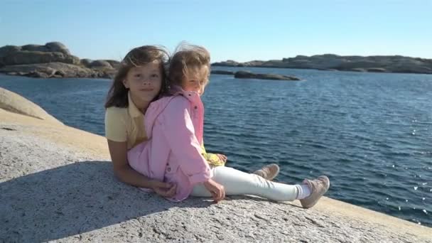 Δύο μικρά κορίτσια παίζουν ανάμεσα στα παραθαλάσσια βράχια στην παραλία. — Αρχείο Βίντεο