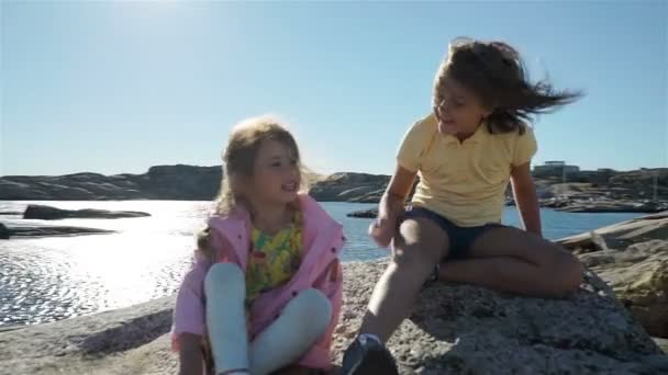 二人の少女がビーチで遊ぶ海岸の岩の間. — ストック動画