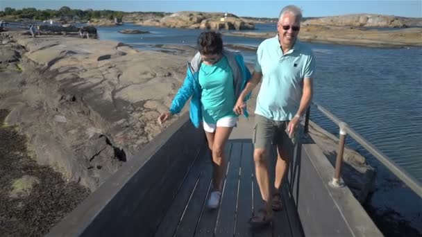 Una feliz pareja madura disfruta de un paseo entre las piedras costeras en la orilla del mar . — Vídeos de Stock