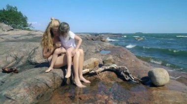 Genç bir kadın ve kızı kaya havuzlarını kıyı kayaların arasındaki sahilde oynuyorlar