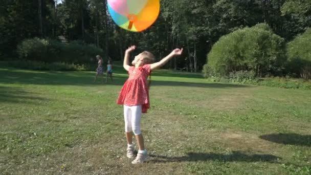 Linda niña jugando con una gran bola inflable de arco iris colorido — Vídeos de Stock