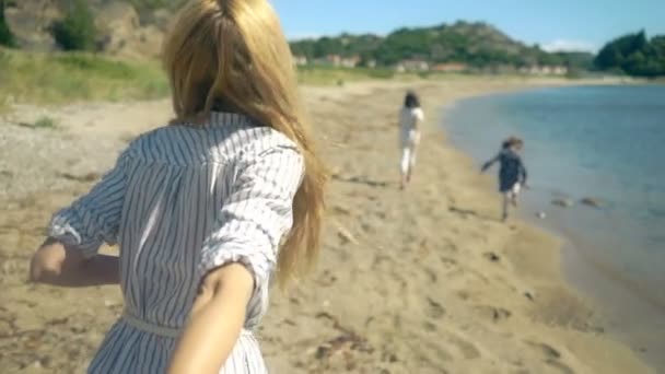 Молодая женщина с детьми ведет мужа к скалистому северному пляжу — стоковое видео