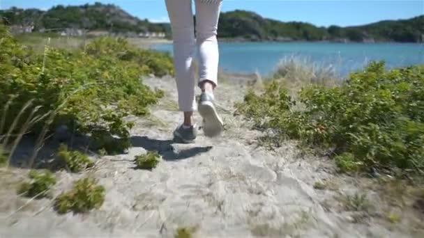 Una joven camina entre las dunas hacia el mar . — Vídeo de stock