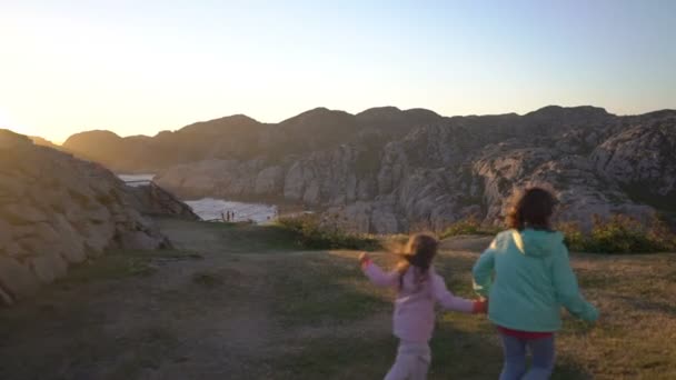 Due bambine giocano su una spiaggia rocciosa del nord . — Video Stock