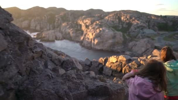 Två små flickor spela på en stenig norra havsstrand. — Stockvideo