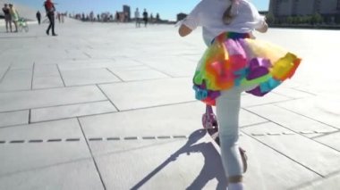 Yanardöner bir parlak etek, küçük bir kız şehirde bir scooter sürme.