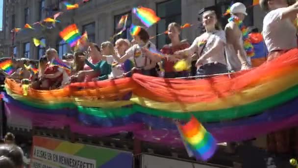 The Pride Parade in Oslo Norway. A lot of fancy-dress people with rainbow flags dance, sing and laugh in the street. — Stock Video