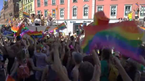 De Pride-Parade in Oslo Noorwegen. Een heleboel gekostumeerd mensen met regenboog vlaggen dansen, zingen en lachen in de straat. — Stockvideo