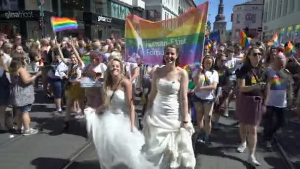 Pride-paraden i Oslo Norge. Många maskeraddräkter människor med regnbåge flaggor dansa, sjunga och skratta i gatan. — Stockvideo