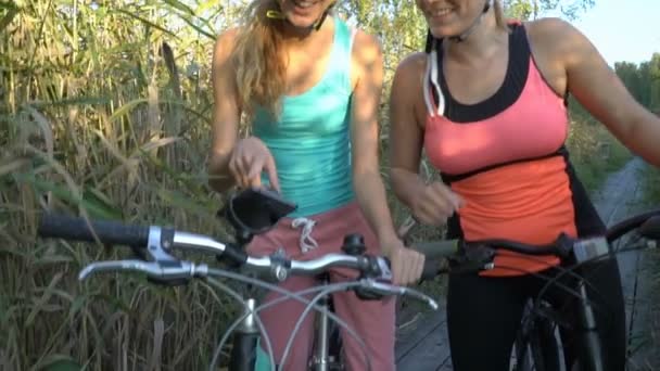 Zwei junge Frauen benutzen GPS-Navigation am Smartphone auf dem Fahrrad beim Radfahren — Stockvideo