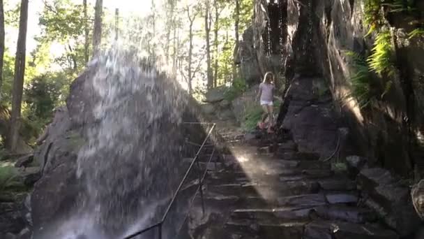 Flicka ha kul körs under strömmar av vattenfallet i nöjesparken — Stockvideo