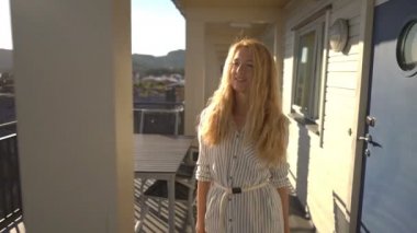 Kuzey Avrupa'nın kıyısında otel terasında deniz manzarasına hayran genç Kızıl saçlı kadın