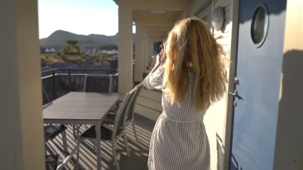 Mujer pelirroja joven tomando fotos en la terraza del hotel en la costa del norte de Europa — Vídeo de stock