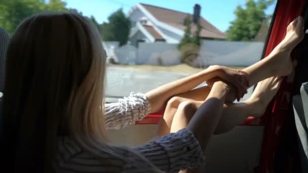 En ung rödhårig kvinna tycker om reser med bil kastar benen på fönstret. — Stockvideo