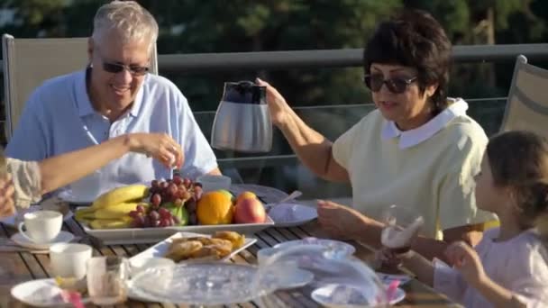 Une grande famille heureuse dîne sur la terrasse ouverte sur le toit de la maison . — Video