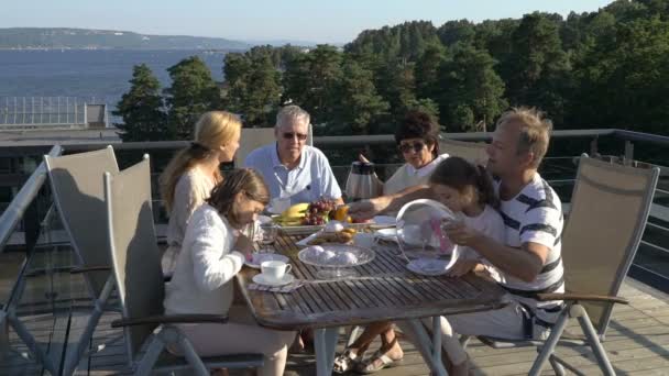 Een grote en gelukkige familie heeft diner op het open terras op het dak van het huis. — Stockvideo