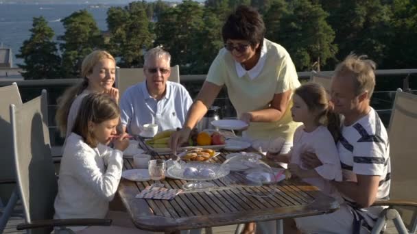 Eine große glückliche Familie speist auf der offenen Terrasse auf dem Dach des Hauses. — Stockvideo