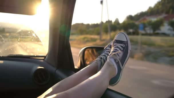 Una mujer joven disfruta viajar en coche asomándose por las piernas en una ventana abierta — Vídeos de Stock