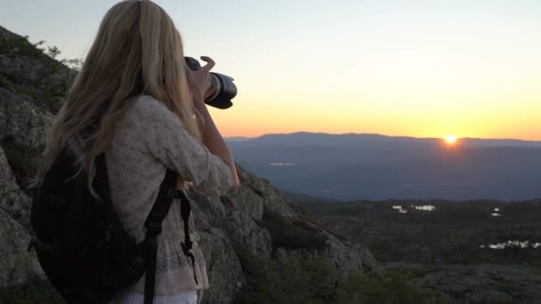 En ung kvinna fotograf fotograferar den solnedgången eller dawn högt i bergen i Norge. — Stockvideo