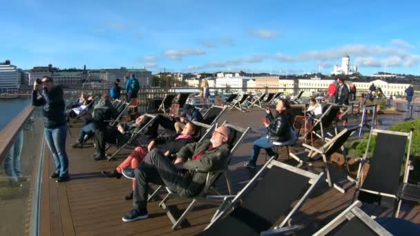 Οι άνθρωποι απολαμβάνουν τις τελευταίες ηλιόλουστες μέρες, που κάθεται στις ξαπλώστρες στο χώρο περιπάτου, το φθινόπωρο στο Ελσίνκι, Φινλανδία — Αρχείο Βίντεο