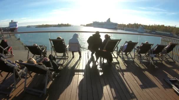 People enjoy the last Sunny days sitting in the sun loungers on the promenade in autumn in Helsinki, Finland — Stock Video