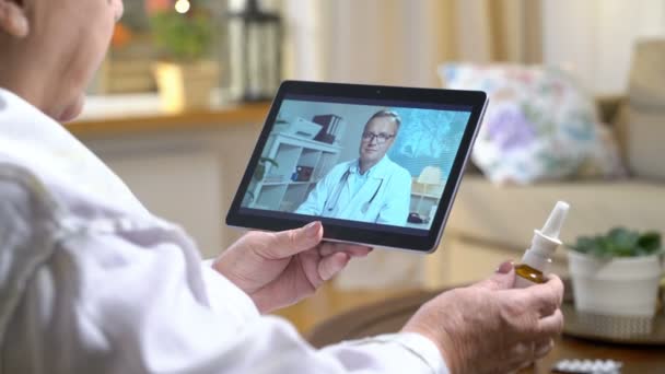 Obat online. Wanita tua berkonsultasi dengan dokternya menggunakan video chat di rumah — Stok Video