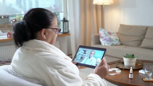 Medicina en línea. Mujer mayor consultando con su médico mediante chat de vídeo en casa — Vídeos de Stock