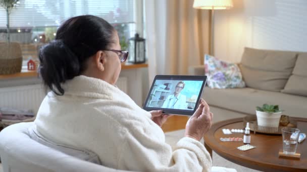 Medicina en línea. Mujer mayor consultando con su médico mediante chat de vídeo en casa — Vídeo de stock