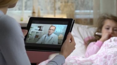 Anne küçük hasta kızı olan alır bir doktorlar konsültasyon evde video sohbet etmek kullanma.