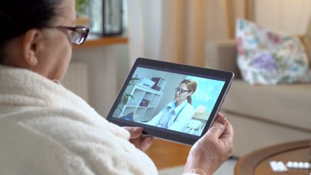 Medicina en línea. Mujer mayor consultando con su médico mediante chat de vídeo en casa — Vídeo de stock