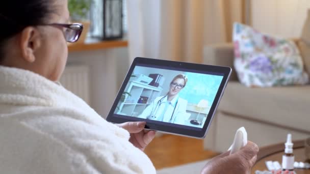 薬を買う。高齢者の女性が家でビデオ チャットを使用して彼女の医者と相談 — ストック動画