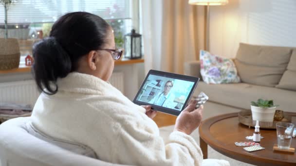 Medicina en línea. Mujer mayor consultando con su médico mediante chat de vídeo en casa — Vídeos de Stock