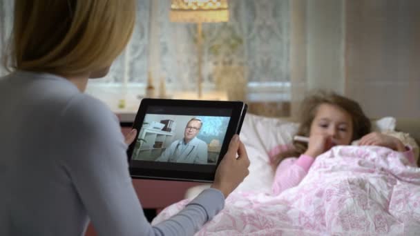 Mamá con una pequeña hija enferma recibe una consulta de médicos usando chat de video en casa . — Vídeos de Stock