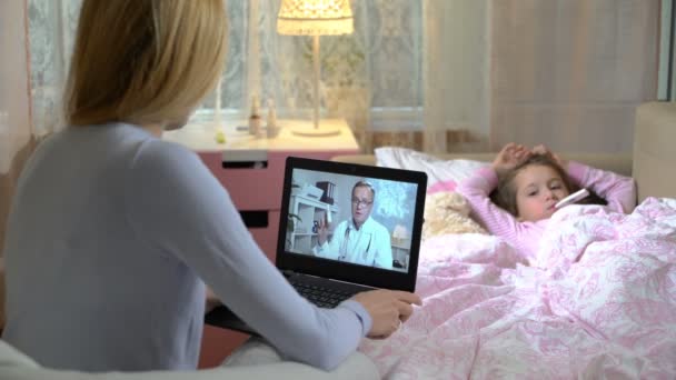 Maman avec une petite fille malade obtient une consultation de médecins en utilisant le chat vidéo à la maison . — Video