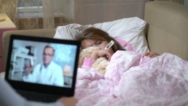 Mom with a little sick daughter gets a doctors consultation using video chat at home. — Stock Video