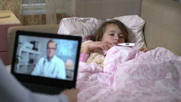 Mom with a little sick daughter gets a doctors consultation using video chat at home. — Stock Video