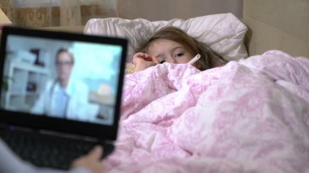 Mamma med en liten sjuk dotter får en läkare samråd använder videochatt hemma. — Stockvideo