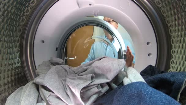 Man loading the the clothes to washing machine. — Stock Video