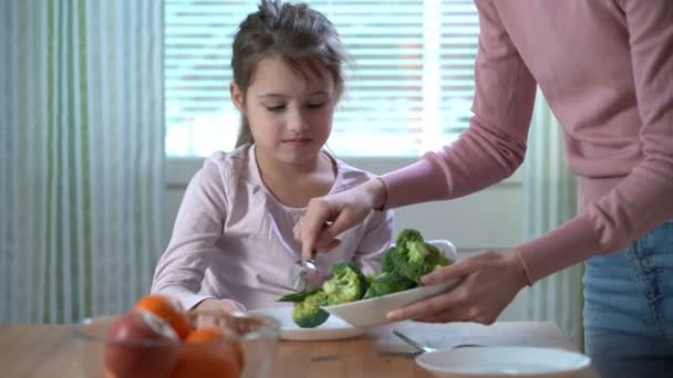 Liten flicka vill inte äta grönsaker och ogillar smaken av broccoli och spenat. — Stockvideo