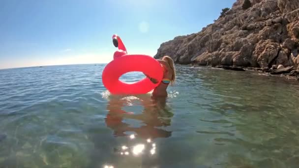 Joven mujer esbelta disfruta del mar y el sol tumbado en un flamenco rosa inflable — Vídeos de Stock