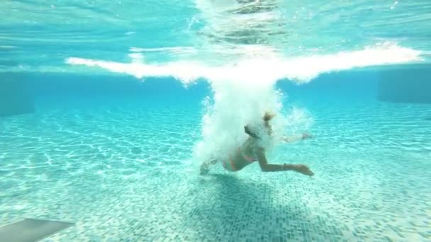 年轻的苗条的女人跳入游泳池, 在水下游泳 — 图库视频影像