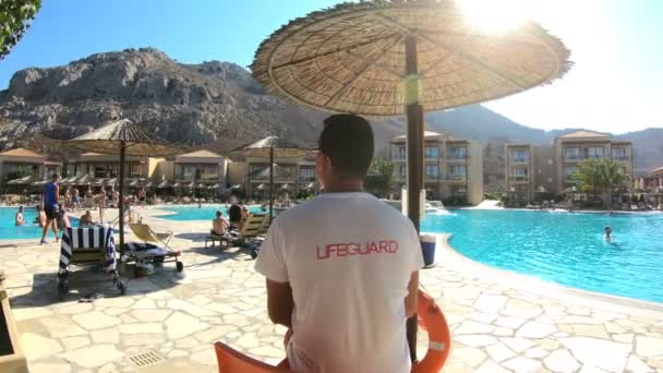 Спасатель у бассейна внимательно следит за туристами в средиземноморском отеле — стоковое видео